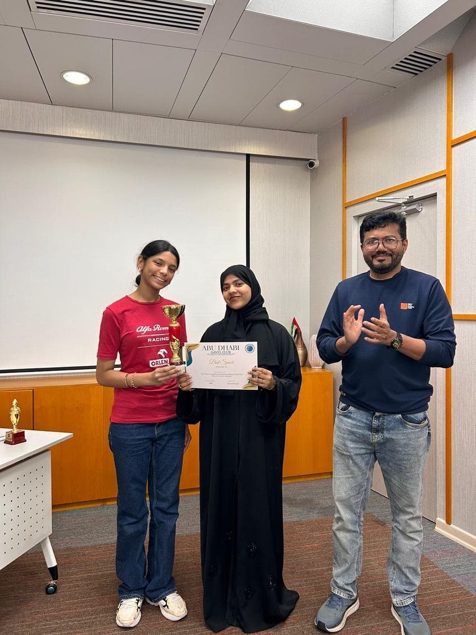 A member holding a trophy and her Best Speech certificate